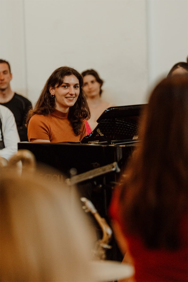 Audience members watching the band up close, a piano behind them